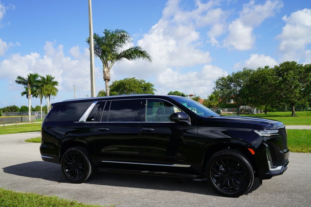 iami Airport limo service with luxury black SUV parked near palm trees