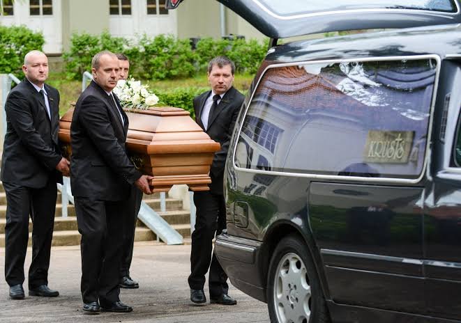 Funeral transportation service with professional pallbearers loading casket into a hearse