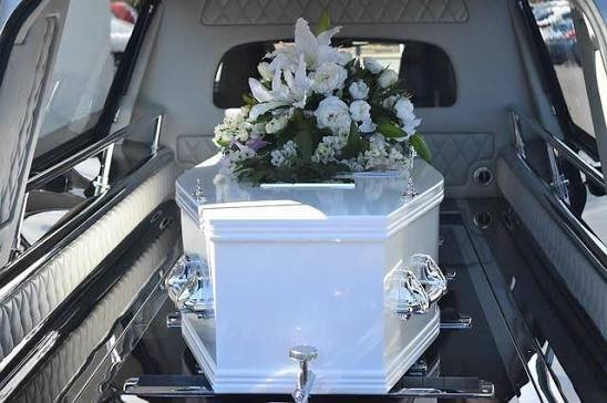 Funeral transportation service with elegant white casket and floral arrangement inside hearse