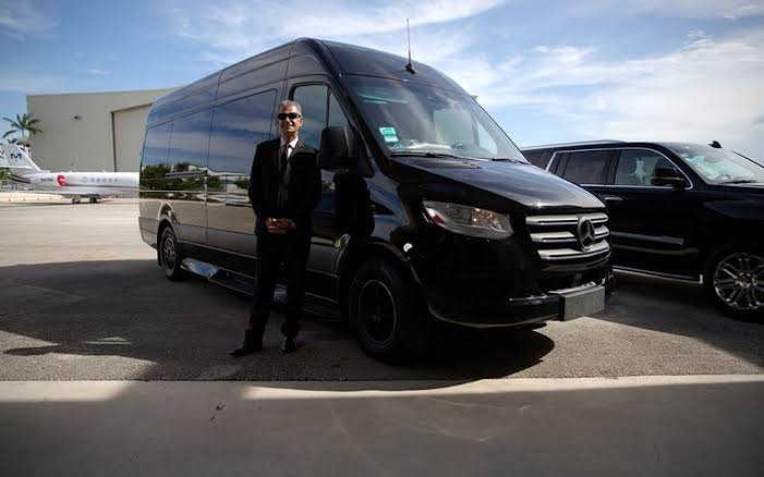 Luxury Sprinter van service with professional driver and black Mercedes van parked on tarmac