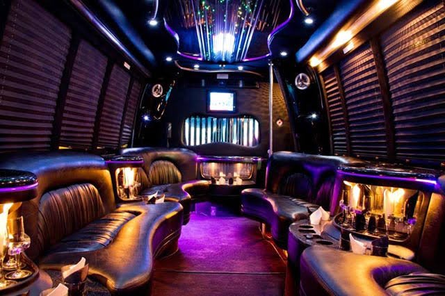 Party bus service interior with purple ambient lighting, leather sofas, and custom bar setup