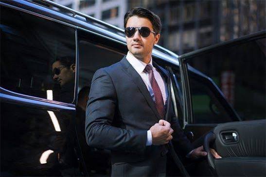 Point to point car service with professional chauffeur standing next to a luxury car